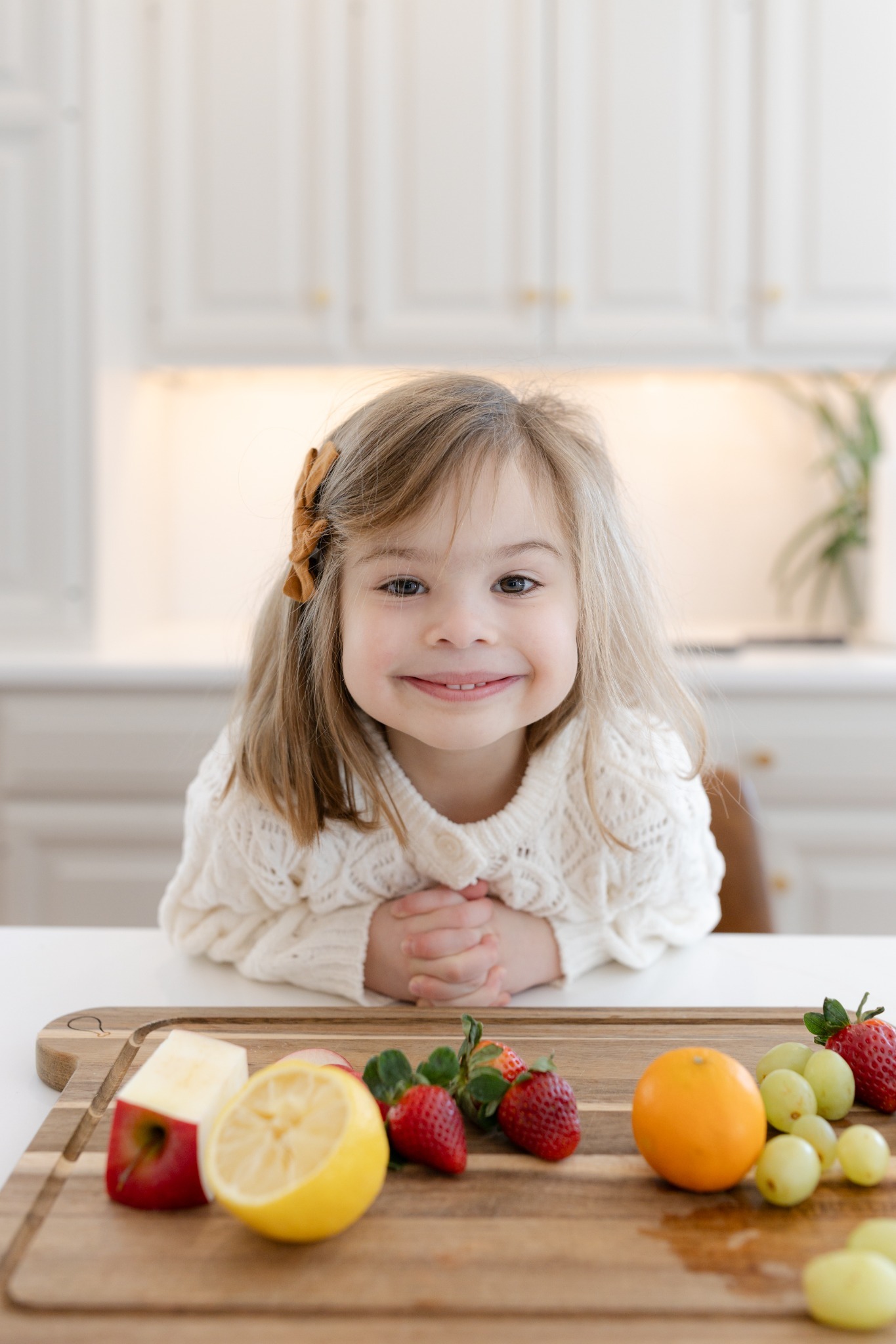 Smiling child sitting at a table with fruit