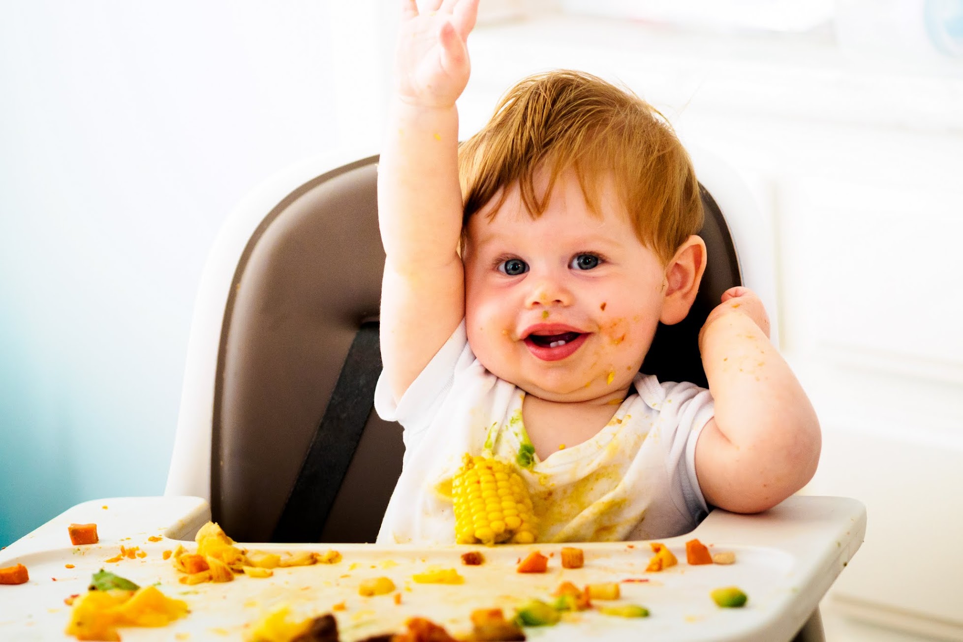 Smiling child eating in a high chair