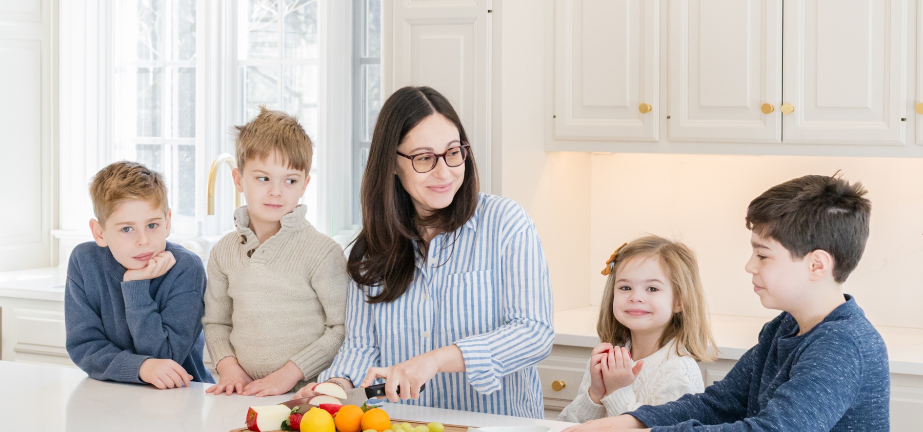 A mother preparing food with her children in the kitchen